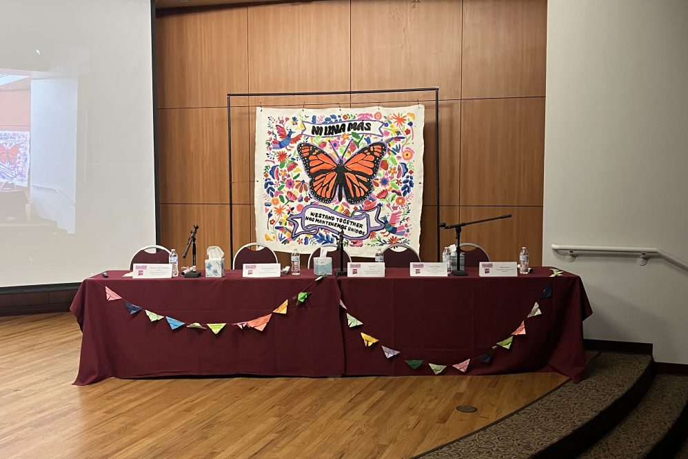 Asientos de los panelistas con mural de mariposa.